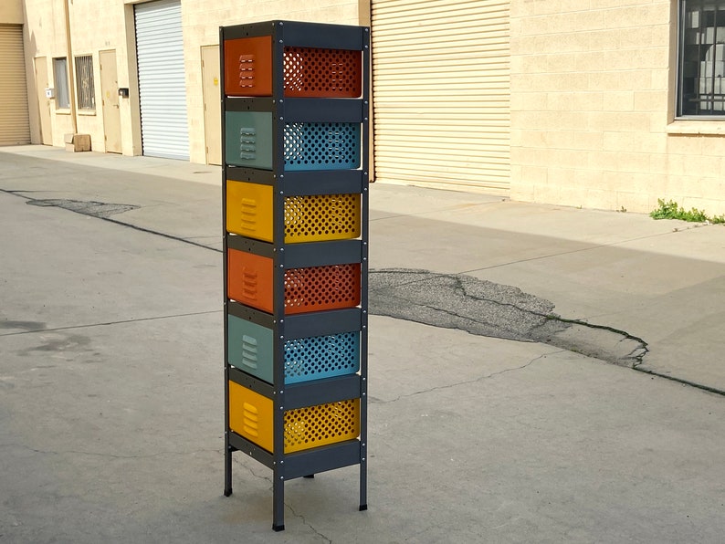 May include: A black metal storage unit with six colorful drawers. The drawers are painted in shades of yellow, orange, and blue. The unit has a simple design and is perfect for organizing small items.