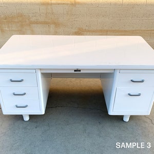 May include: White metal desk with three drawers on each side. The desk has a white top and silver drawer pulls. The desk is sitting on a concrete floor. SAMPLE 3.