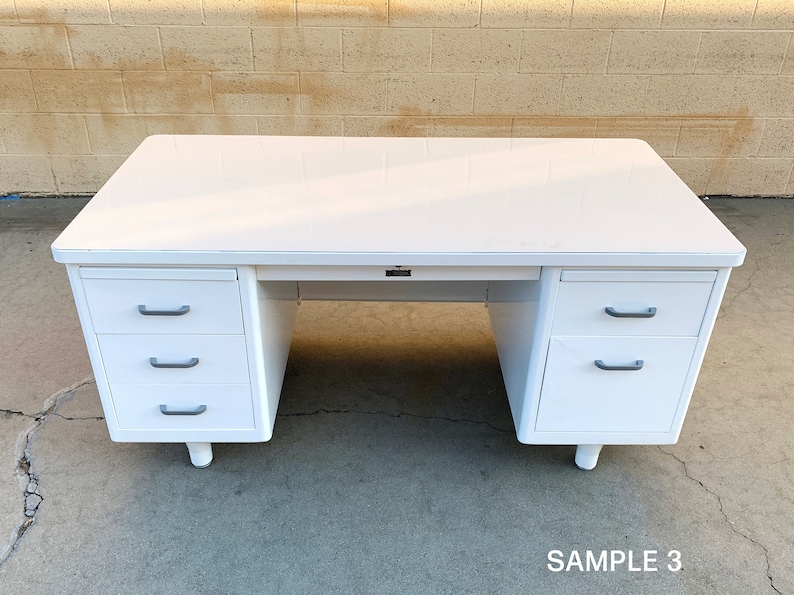 May include: White metal desk with three drawers on each side. The desk has a white top and silver drawer pulls. The desk is sitting on a concrete floor. SAMPLE 3.