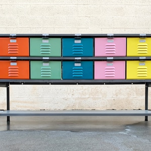 Puede incluir: Una unidad de almacenamiento de metal con dos estantes y doce cajones de colores. Los cajones están pintados en tonos de naranja, verde, azul, rosa y amarillo.