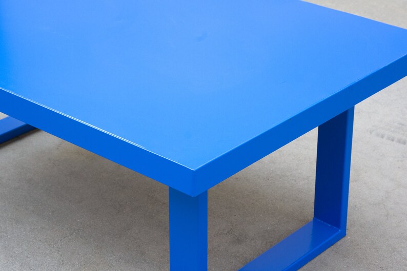 May include: A modern, bright blue table with a rectangular top and square legs. The table is painted in a solid, vibrant blue color. The table's dimensions are not visible in the image.