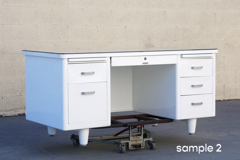 May include: White metal desk with a glass top and three drawers on each side. The desk is on a rolling dolly.