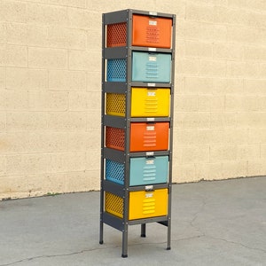 May include: A six-drawer metal storage unit with a black frame. The drawers are painted in various colors, including orange, yellow, and blue.