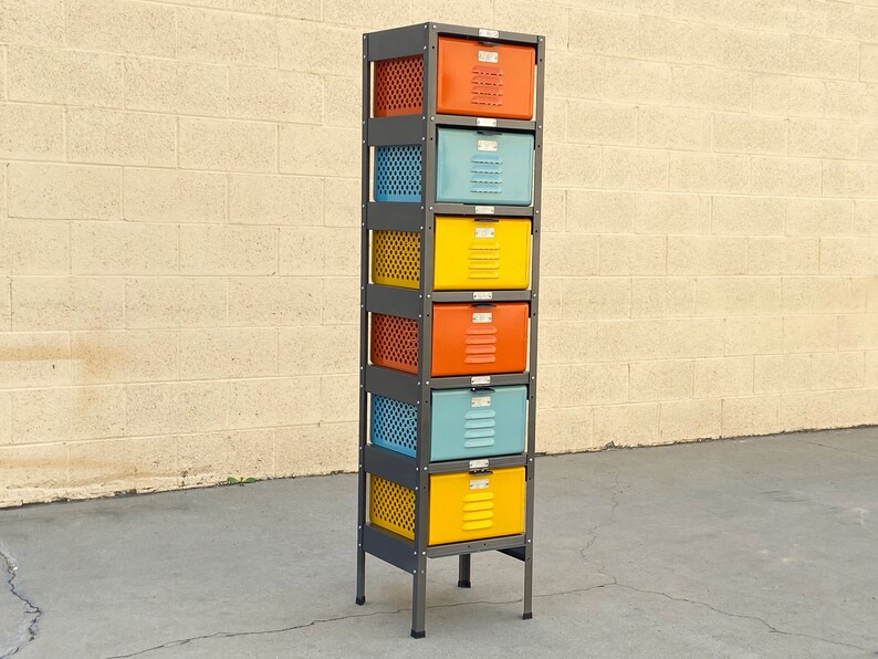 May include: A six-drawer metal storage unit with a black frame. The drawers are painted in various colors, including orange, yellow, and blue.
