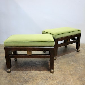 May include: Two rectangular ottomans featuring lime green upholstered cushions and dark brown wooden frames. Each piece is supported by four legs, with each leg ending in a small, round, metallic caster wheel for mobility and support.