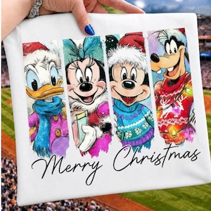 May include: A white fabric item featuring a watercolor-style graphic of four cartoon characters wearing winter clothing, including hats and scarves. The text Merry Christmas is printed in black script below the characters on the white background.