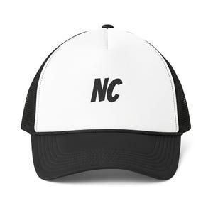 Könnte beinhalten: Eine Trucker-Cap mit weißem Vorderteil, auf dem mittig die schwarzen Buchstaben NC aufgedruckt sind. Die Kappe hat einen schwarzen Schirm, schwarze Netz-Seitenteile sowie ein schwarzes Rückenteil und einen schwarzen Knopf an der Oberseite.