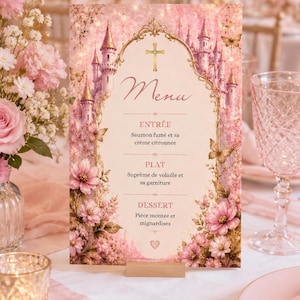 May include: A pink and gold menu card with a castle design, flowers, and butterflies. The menu includes the words "Menu", "Entrée", "Plat", and "Dessert". The card is propped up on a wooden stand.