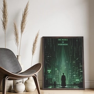 May include: A rectangular framed wall art print featuring a dark green digital cityscape with a silhouette of a person standing in the center. The text reads THE MATRIX IS EVERYWHERE, WAKE UP, and MATRIX in a glowing green font against the dark background.