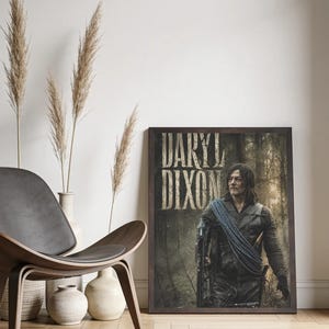 May include: A rectangular framed poster featuring a portrait of Daryl Dixon in a dark forest setting. The character wears a dark vest and carries a crossbow with blue rope draped over the shoulder. The text DARYL DIXON appears in large letters.