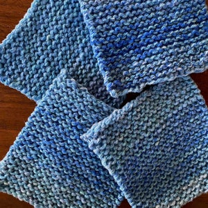 May include: Four blue knitted squares with a gradient of color from light blue to dark blue.