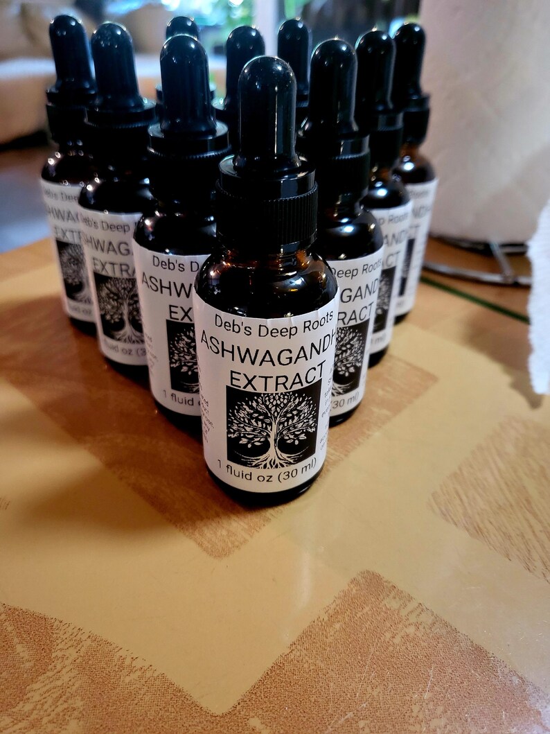Pu&ograve; includere: Una collezione di bottiglie di vetro marrone con contagocce neri. Ogni bottiglia ha un'etichetta bianca con il testo "Deb's Deep Roots ASHWAGAND EXTRACT" e una grafica ad albero. Le bottiglie contengono 30 ml.