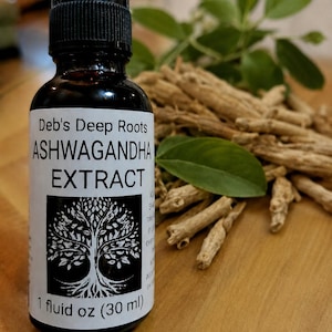 Pu&ograve; includere: Una bottiglia di vetro nero di estratto di Ashwagandha Deb's Deep Roots con un contagocce. L'etichetta presenta un disegno ad albero. La bottiglia &egrave; da 30 ml. Radici di Ashwagandha e foglie verdi sullo sfondo.