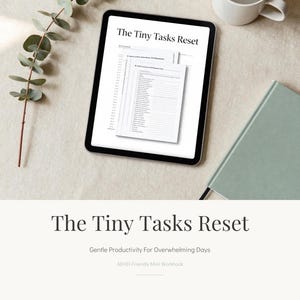 Può includere: Un tablet digitale mostra un quaderno di lavoro intitolato "The Tiny Tasks Reset". L'immagine include una tazza bianca, un taccuino verde e un rametto di verde. Il quaderno di lavoro è progettato per una produttività delicata per le giornate opprimenti.