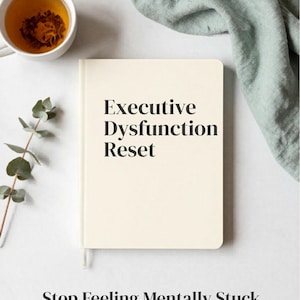 Può includere: Un taccuino color crema con il titolo "Executive Dysfunction Reset" in grassetto nero. L'immagine include una tazza di tè, un rametto di verde e un panno verde piegato. Sotto il taccuino, il testo recita "Stop Feeling Mentally Stuck".