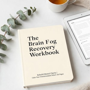 Può includere: Un quaderno color crema intitolato "The Brain Fog Recovery Workbook" con il testo "Rebuild Mental Clarity | Calm Your Overstimulated Mind | 60 Pages." Una tazza di tè e un tablet sono anche nell'immagine.