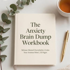 Può includere: Un quaderno color crema intitolato "The Anxiety Brain Dump Workbook" con il testo "Release Mental Overwhelm | Calm Your Anxious Mind | 35 Pages." Una penna d'oro e una tazza di tè sono accanto al libro.
