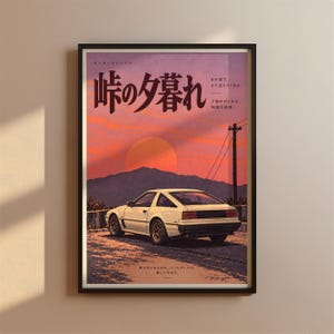 May include: A framed poster featuring a white sports car parked on a road at sunset. The background shows mountains and a large orange sun. Japanese text is printed at the top and bottom, including the large characters 峠の夕暮れ, with a utility pole on the right side of the composition.