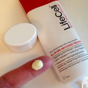 May include: A white tube of LifeCell anti-aging cream with a red cap and the text "LifeCell South Beach Skincare". A small amount of cream is on a finger. The tube is 75 ml.