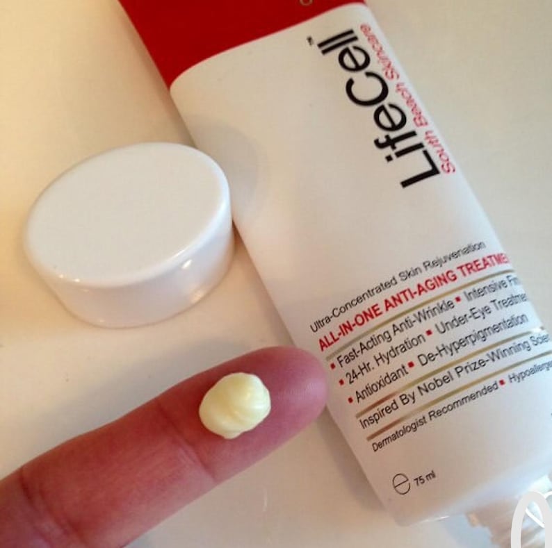 May include: A white tube of LifeCell anti-aging cream with a red cap and the text "LifeCell South Beach Skincare". A small amount of cream is on a finger. The tube is 75 ml.