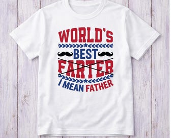 May include: White t-shirt with a humorous graphic. The design features the text "WORLD'S BEST FARTER I MEAN FATHER" in red and blue, with two black mustache illustrations. The shirt is made of a soft material.
