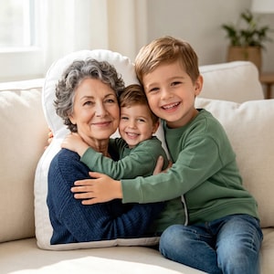 May include: A custom-shaped throw pillow featuring a printed photograph of an older person with gray hair wearing a dark blue sweater, embracing a young child in a green long-sleeved shirt. The pillow has a white border and soft fabric texture.