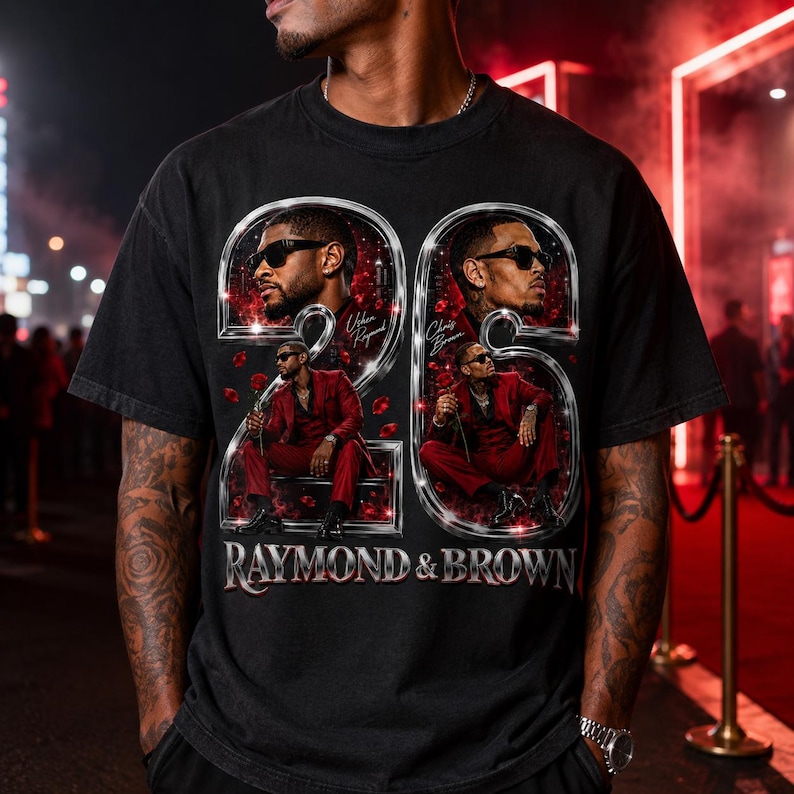 May include: A black short-sleeve t-shirt featuring a graphic print of two men in red suits, each framed within a large metallic number 2. The design includes the text "Usher Raymond," "Chris Brown," and "RAYMOND & BROWN" with red rose petals.
