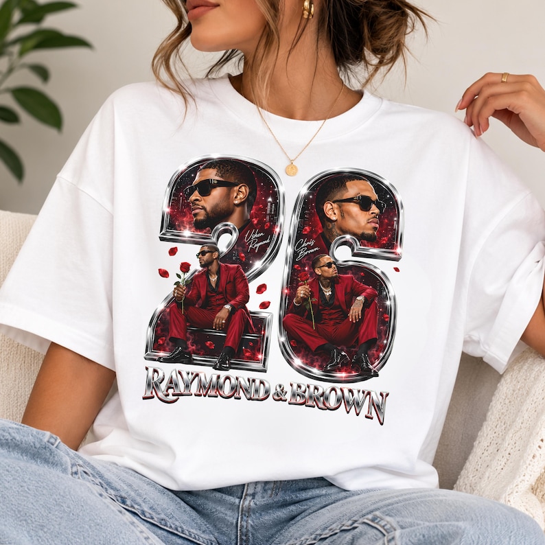 May include: A white t-shirt featuring a graphic print of the number 26 in a metallic chrome style. Inside the numbers are portraits of two men in red suits and sunglasses, with red rose petals scattered around. The text RAYMOND & BROWN is below.