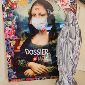 Peut inclure: Une œuvre d'art encadrée représentant une Mona Lisa réinventée portant un masque facial, avec des éléments de style graffiti et les mots "TIME TO MONEY". Une statue argentée d'une figure en prière se trouve à côté.