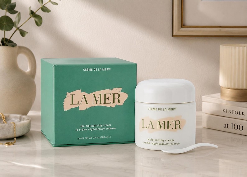 La Mer Crème de La Mer Moisturizing Cream with original green box displayed on a marble table with elegant home décor and neutral wall background.