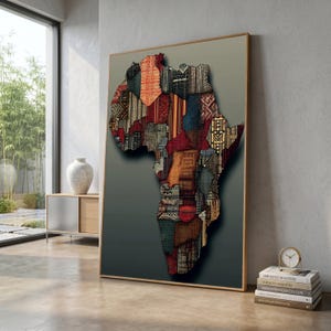 Puede incluir: Una obra de arte enmarcada que representa el continente africano. El mapa está compuesto por varios patrones de tela en tonos rojos, naranjas, azules y marrones. La obra de arte está sobre un fondo degradado y enmarcada en un marco dorado.