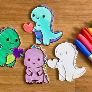 Peut inclure: Plusieurs découpes en forme de dinosaures aux couleurs vives, chacun tenant un cœur. Les dinosaures sont verts, bleus, violets et blancs. Un ensemble de marqueurs Sharpie de différentes couleurs est également présent.