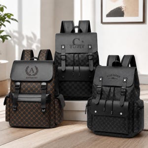 May include: Three backpacks with flap closures and buckle straps. The left bag is brown with a repeating pattern and the name ANTHONY. The center bag is black with a checkerboard pattern and the name OLIVER. The right bag is black with the name ALEXANDER.