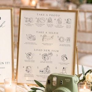 Op de afbeelding: Twee goudkleurige borden met zwarte tekst en lijntekeningen van een camera. Het linkerbord toont Polaroid guestbook, Snap it! Stick it! Sign it! en Sophie + Harry. Het rechterbord geeft instructies voor het maken van foto's en het laden van film. Een saliegroene instantcamera staat ernaast.