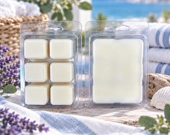 Pode incluir: Dois recipientes de plástico transparente com ceras aromáticas em tom esbranquiçado. Um contém seis cubos de cera quadrados individuais e o outro um bloco retangular grande, ambos concebidos para usar num queimador.