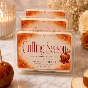 May include: A clear plastic clamshell package containing wax melts with a label reading Cuffing Season, Apple, Caramel, Vanilla Bean, Howl + Ember Premium Wax Melt, Net Wt. 2.5 oz (71g). The label features a caramel apple illustration.