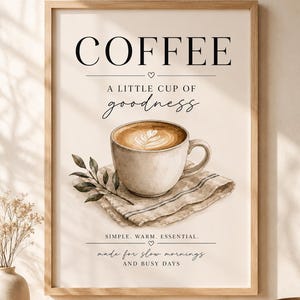 Könnte beinhalten: Ein gerahmter Kunstdruck mit einer Aquarellillustration einer Kaffeetasse auf einer Serviette mit einem kleinen Blattzweig. Der Text lautet: COFFEE, A LITTLE CUP OF goodness, SIMPLE. WARM. ESSENTIAL., made for slow mornings AND BUSY DAYS.
