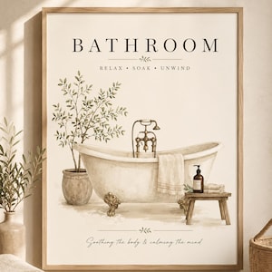 Op de afbeelding: Een ingelijste wandprint met een bad op pootjes met een koperen kraan, een plant in een pot en een houten krukje met een fles en handdoek. De tekst luidt BATHROOM, RELAX • SOAK • UNWIND en Soothing the body & calming the mind.