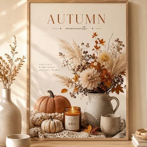 May include: A framed wall art print titled AUTUMN moments featuring a bouquet of dried flowers, pampas grass, and autumn leaves in a ceramic pitcher. The scene includes a pumpkin, a small gourd, a lit candle, and a mug on a textured knit fabric.