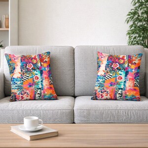 May include: Two decorative throw pillows with vibrant floral and abstract patterns in shades of pink, orange, blue, and green. The pillows are square and rest on a gray sofa, adding a pop of color to the room.
