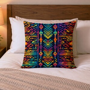 May include: A square pillow with a vibrant, geometric pattern in shades of blue, yellow, orange, and red. The pillow is placed on a white bed with a wooden headboard and a beige blanket.