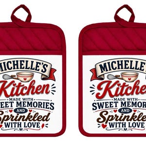 May include: Two rectangular red quilted pot holders with a white center panel. The text reads: MICHELLE'S Kitchen MADE WITH SWEET MEMORIES AND Sprinkled WITH LOVE. The design includes a small mixing bowl, a whisk, and several small red hearts.