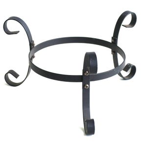 May include: A black metal plant stand with a circular top and three curved legs. The stand features decorative scrollwork and is designed to hold a pot or container. The stand is approximately 12 inches in diameter.