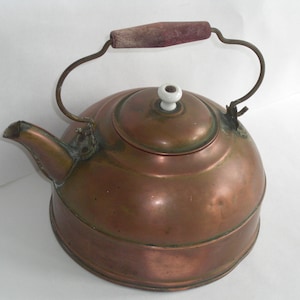 May include: A vintage copper tea kettle with a wooden handle and a white porcelain knob on the lid.