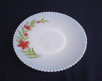 May include: A white milk glass saucer with a blue scalloped edge and a hand-painted design of red flowers and green leaves.