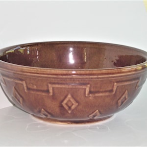 May include: A brown ceramic bowl with a diamond pattern. The bowl is glazed and has a smooth finish.