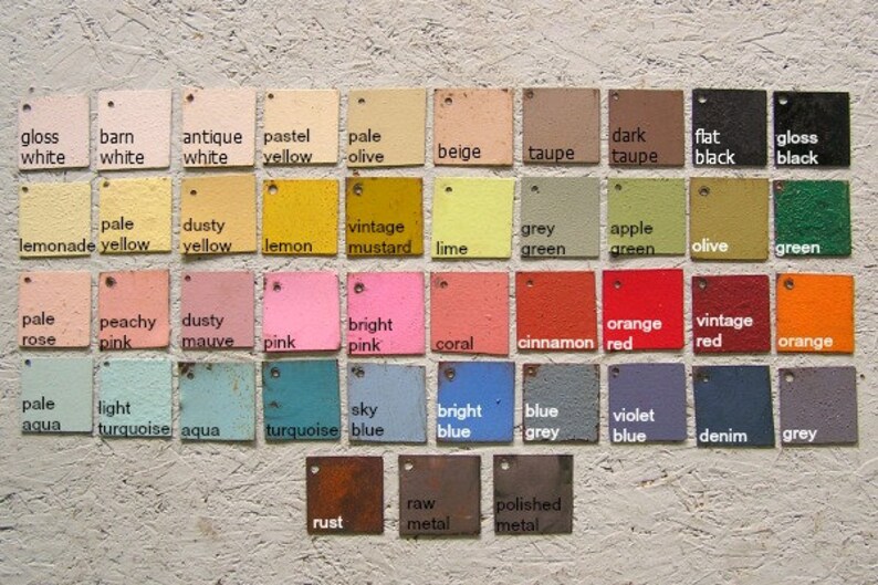 May include: A collection of painted color swatches in various shades, including white, yellow, pink, blue, green, and brown. Each square has a small hole for hanging and a label with the color name.