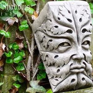 Könnte beinhalten: Eine graue Steinskulptur eines Green Man-Gesichts mit detaillierten Blatt- und Gesichtsmerkmalen. Die Skulptur befindet sich vor einem Hintergrund aus Efeu und einer Steinmauer. Der Text "Cast Shadows Studio" ist sichtbar.