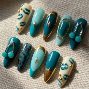 May include: A set of ten almond-shaped press-on nails featuring a variety of designs including cream nails with green lip prints, solid teal nails, teal nails with gold star charms, teal nails with gold cherry charms, and teal leopard print patterns.