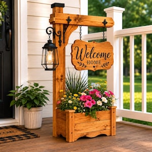 Puede incluir: Un soporte de madera para porche con un letrero colgante rectangular con el texto Welcome Home, una linterna de metal negro y una jardinera rectangular llena de flores rosas, blancas, amarillas y follaje verde.